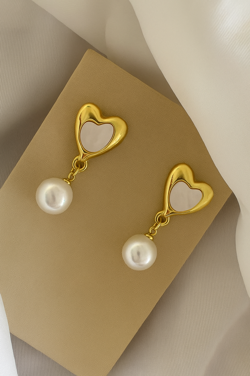 Brinco formato de coração dourado e detalhe em madrepérola.