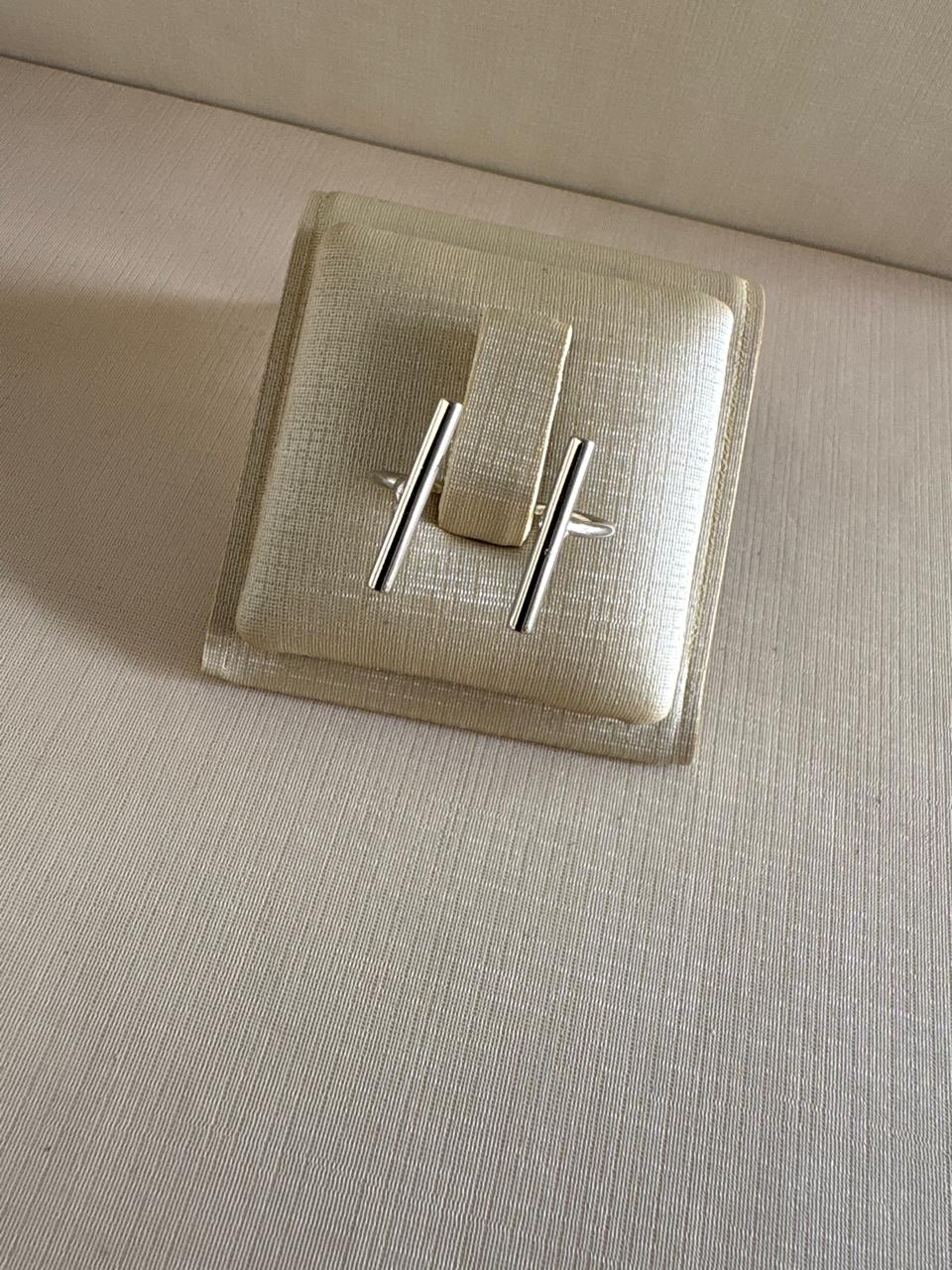 Anel geométrico com duas barras prateada.