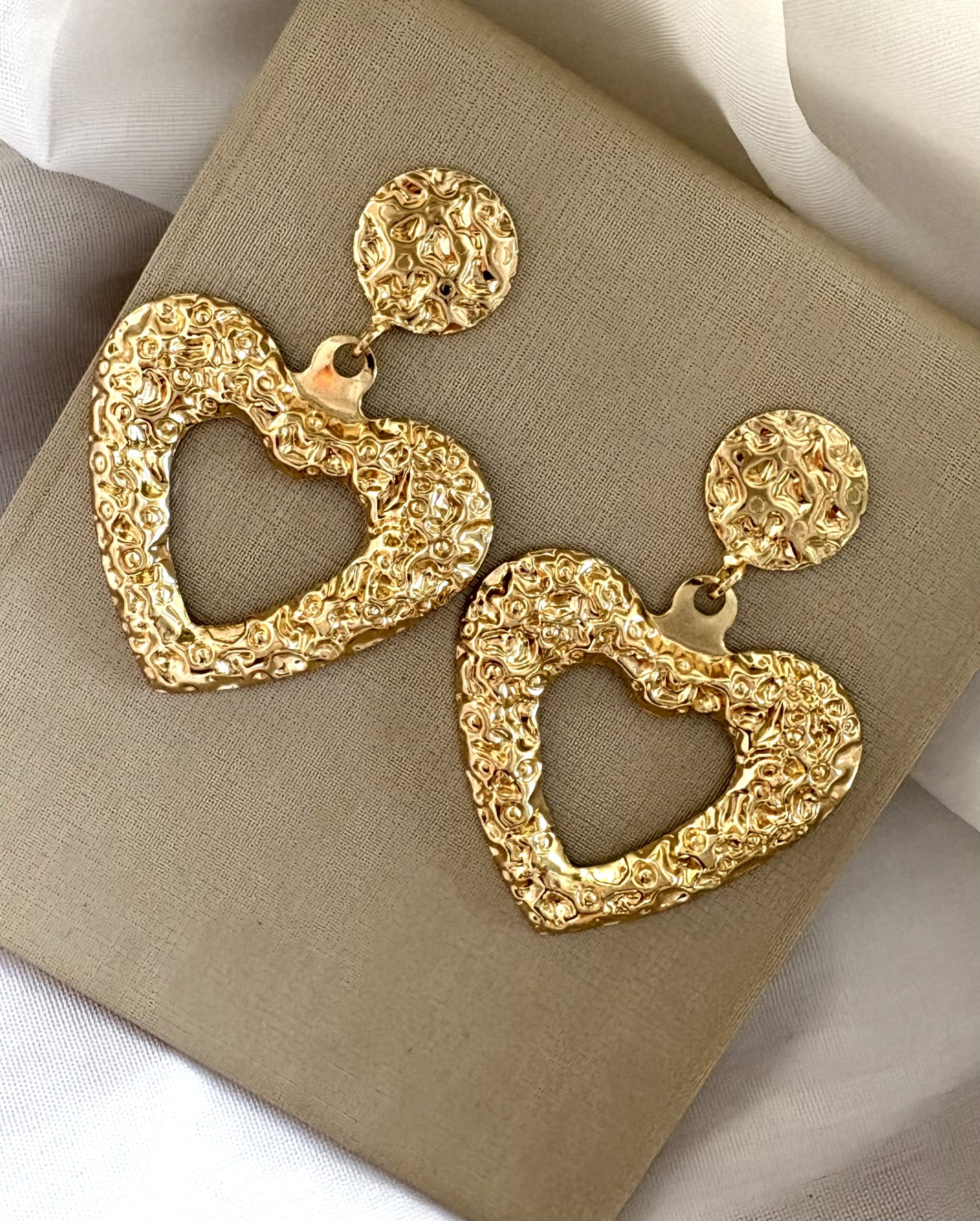 Brinco coração vazado dourado.