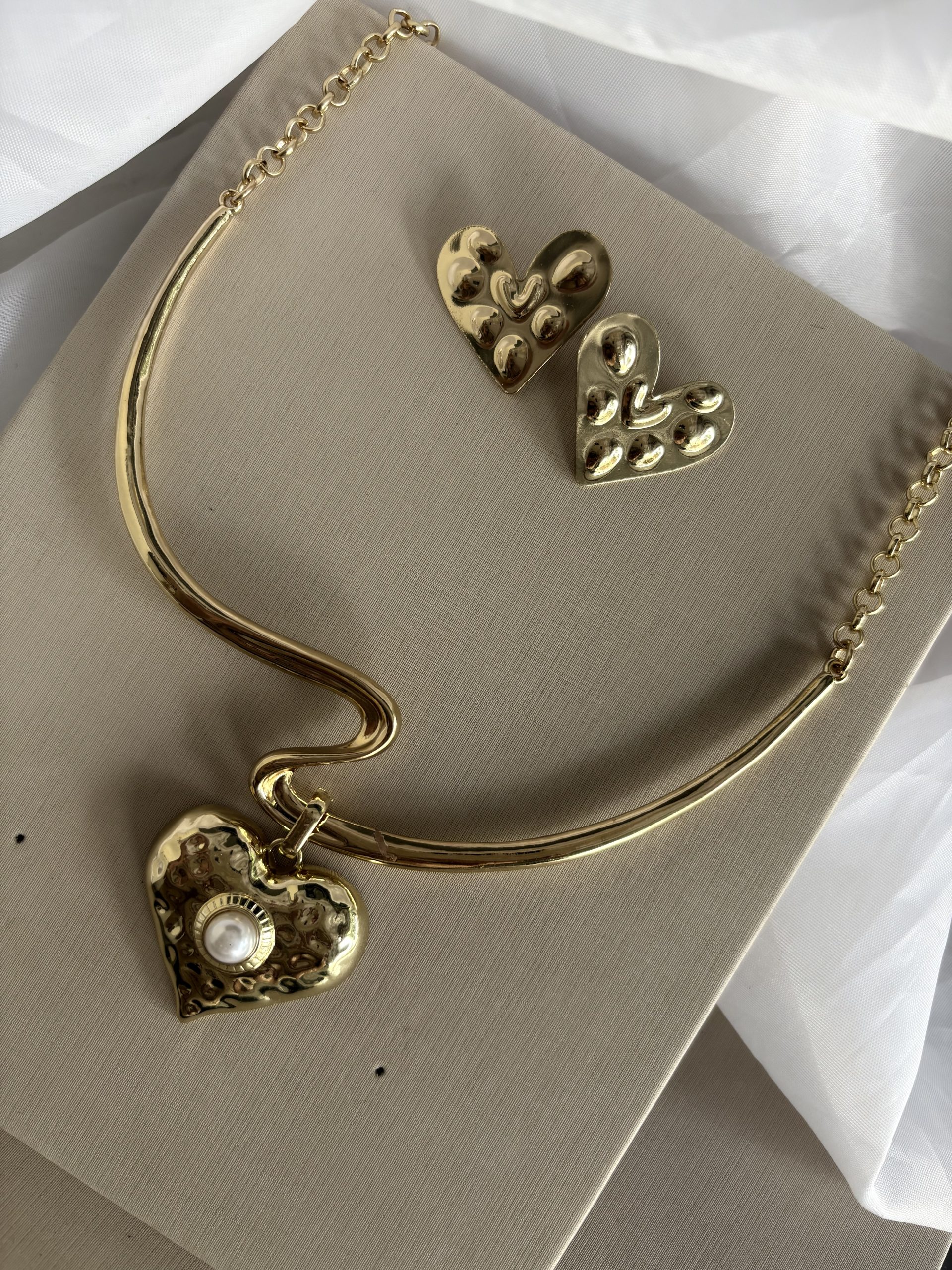 Conjunto de colar com brinco em formato de coração na cor dourado.