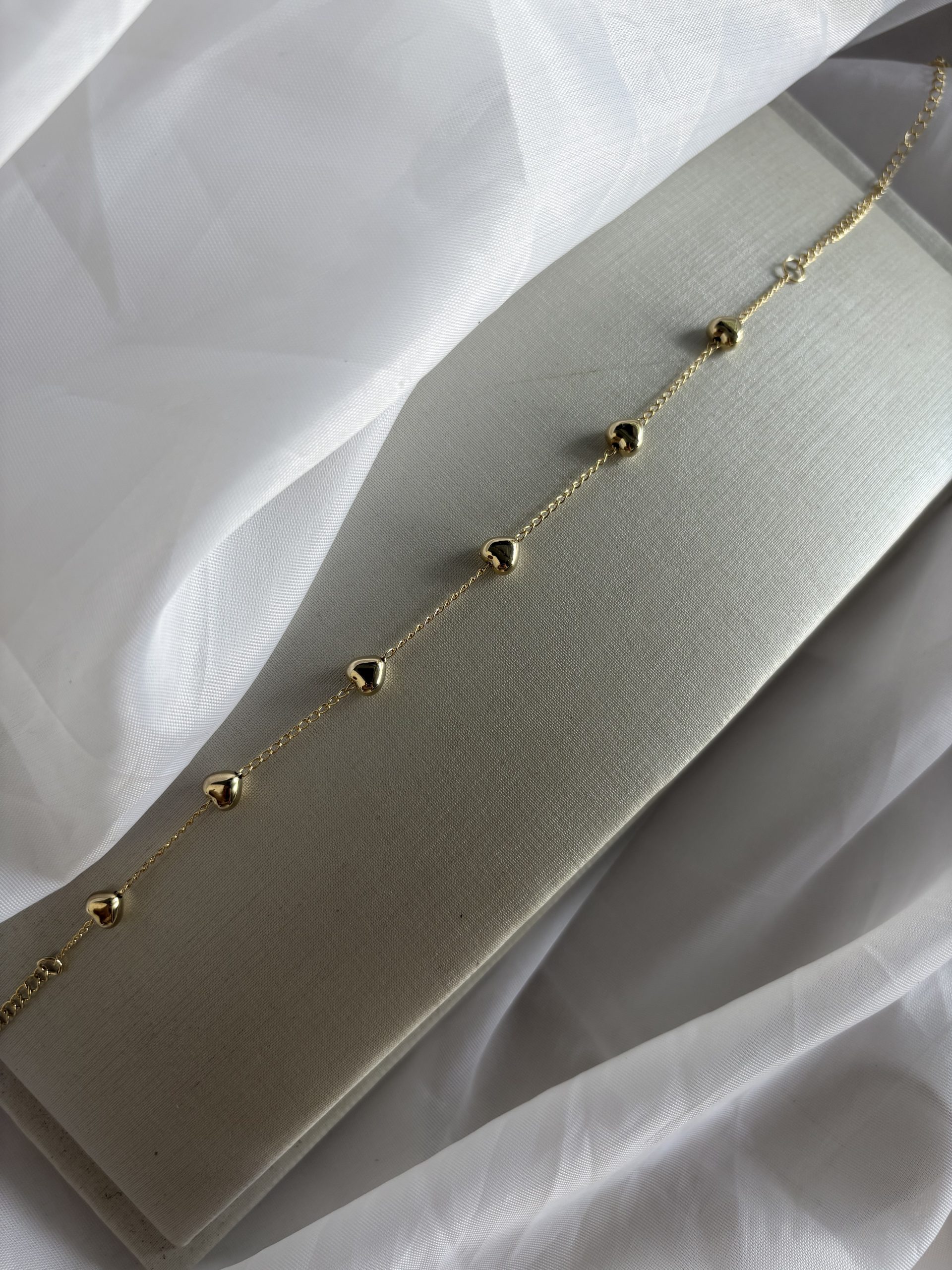 Choker dourada com coraçõezinhos delicados.