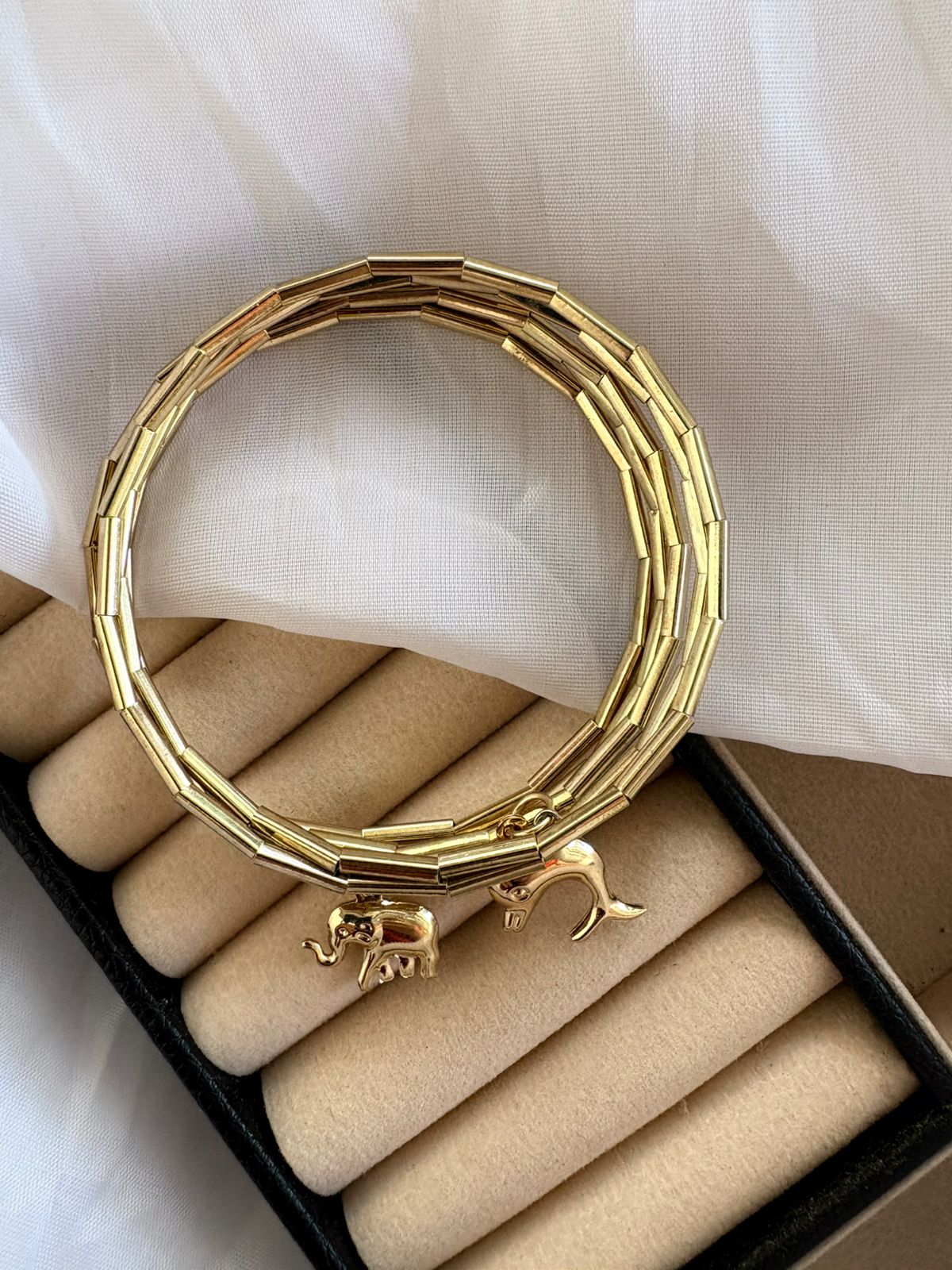 Pulseira dourada com pingentes de elefante e golfinho.