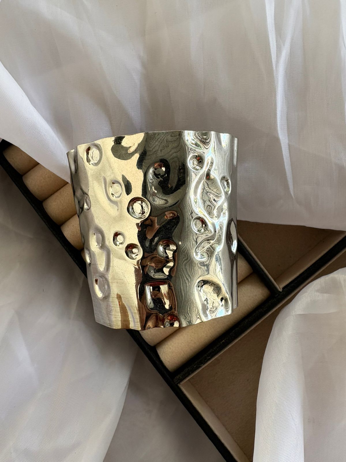 Bracelete prateado com textura martelada.